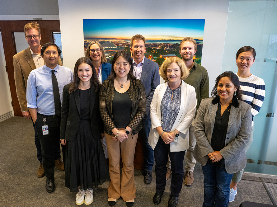 A diverse group of people stand and smile for a group photo.