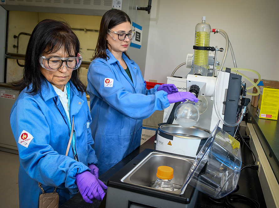 Two women collaborate on setting up an experimental station.