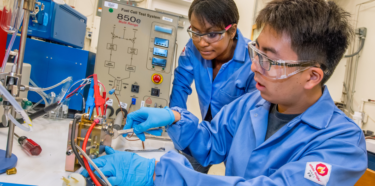 A man and a woman install test equipment in a laboratory together.