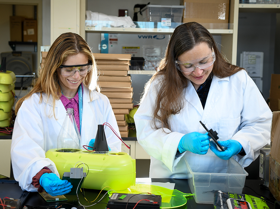 Two researchers looking down and smiling at science equipment